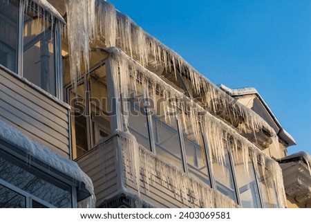 Balconies of a residential apartment building covered with large icicles in the winter season, large heat loss from the house