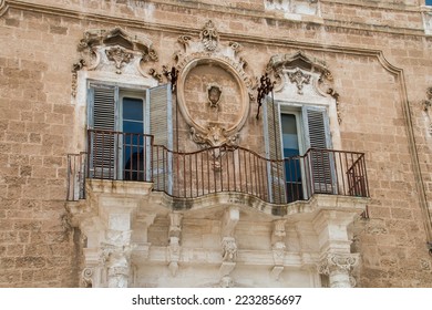 Balcony of the 18th century Palazzo Palmieri in Monopoli, Italy. Rich architectural and artistic details carved in marble and aged by the weather.