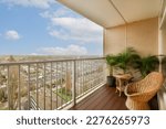 a balcony with a chair and potted plant on the outside deck looking out over a cityscapea