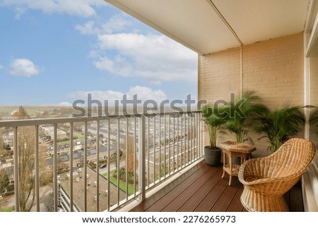 a balcony with a chair and potted plant on the outside deck looking out over a cityscapea