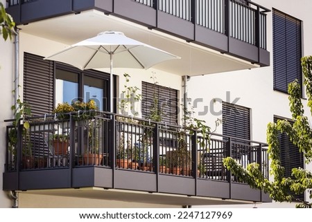 Balcony of European Modern Apartment Building with Shutters Outdoor or Roller Blinds,  Flower Pots. Urban Balcony Garden. Exterior Balcony of Residential House Facade.