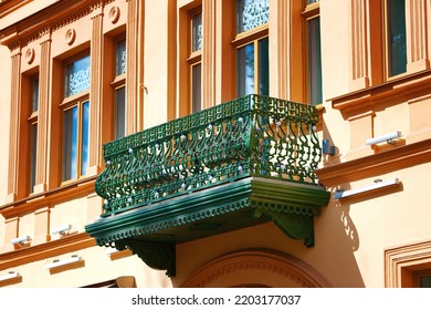 Balcony made of cast iron with decorative elements. Cast iron green balcony of old urban house. Old balcony on building facade with cast iron ornaments. Facade of the house with windows and balconies. - Shutterstock ID 2203177037