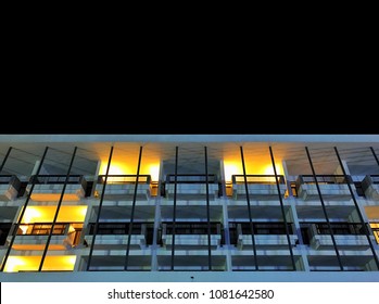 Balcony Pattern Of Low Rise Hotel Building Exterior With Dark Night Sky Background, Lighting At Room Terrace With Steel Fence And Pole, Low Angle View From Outdoor, No People, Feel Lonely Emotion