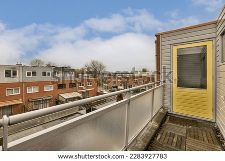a balcony with some buildings in the background and a yellow door on the right side that leads to an apartment