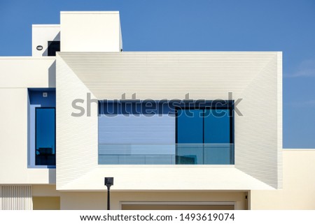 Balcony of a white and blue modern villa in a Middle Eastern, high-end, luxury housing development on a sunny day with strong shadows.