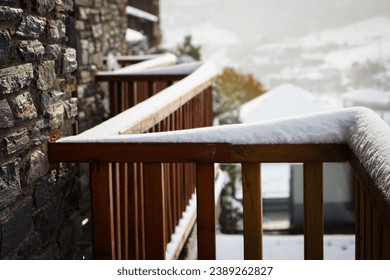 balcony with a wooden railing covered in snow, you can see snowy gabled houses and in the background a mountain with snowy bushes while the mist comes down the hill. - Powered by Shutterstock