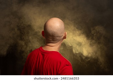 Bald bearded man wearing red shirt with his back to the camera. Studio portrait. Yellow colored background with artificial smoke. - Powered by Shutterstock