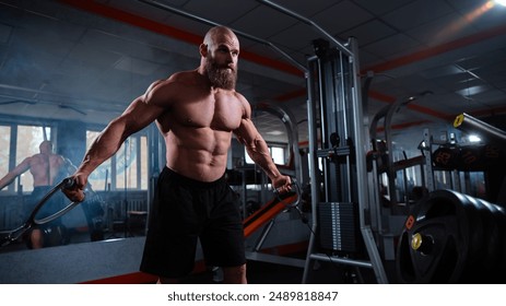 Bald Caucasian bodybuilder training chest using cable crossover in gym. 