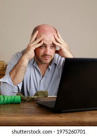 A Bald, Caucasian Male, 30-39 Years Old, Looking At A Notebook Frustrated, Clutching His Head, Trying To Learn Online How To Knit Wool Clothing.