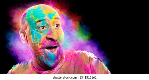 Bald Cheerful Man With Colored Face Celebrating Holi Color Festival. Man Having Fun With Colorful Powder. Portrait With Copy Space For Your Text