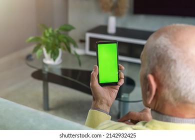 Bald Elderly Man Holds Smart Phone With Empty Green Screen For Mockup