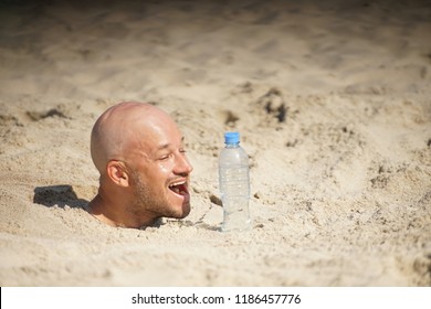 the bald guy is buried in the sand vertically, the body is in the sand, the head is outside, in sunny weather on the beach with a bottle of water