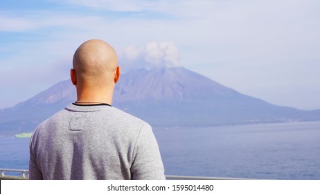 
bald guy in casual clothes on a background of a smoking volcano on a sunny day in Japan. volcano eruption 