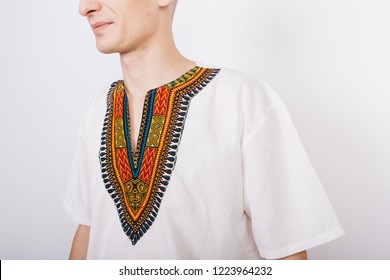 bald guy in the national African costume-dashiki. emotional portrait of a student. smiling male animator posing on white background. clothes for party and fashion show