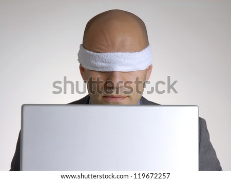 Bald head man blindfolded using a computer.