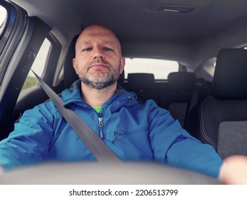 Bald Male Car Driver In Blue High Visibility Hiking Jacket. The Model In His 40s With Grey Beard. Travel And Tourism Concept. Driver Wearing Safety Belt.