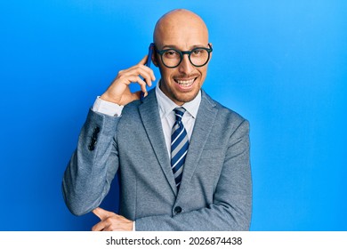 Bald man with beard having conversation talking on the smartphone looking positive and happy standing and smiling with a confident smile showing teeth  - Shutterstock ID 2026874438
