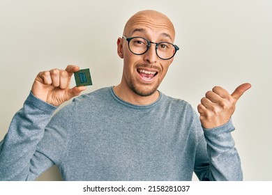 Bald Man With Beard Holding Cpu Computer Processor Pointing Thumb Up To The Side Smiling Happy With Open Mouth 