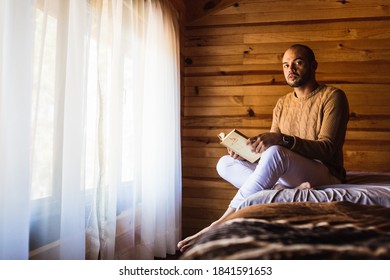 Bald Man With A Beard Reading A Book With A Sweater For The Cold