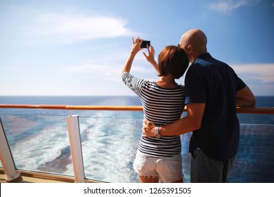 bald man and brunette woman traveling on cruise liner ship and taking pictures from smartphone on balcony  - Powered by Shutterstock