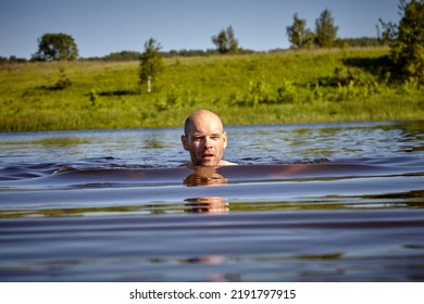 A Bald Man Is Floating On A River On A Hot Summer Day.