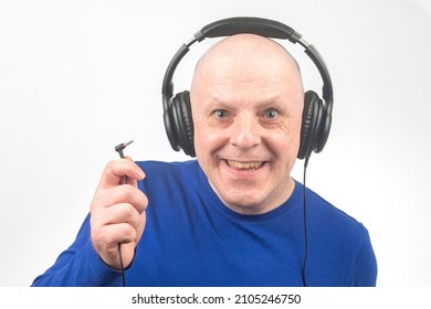 Bald Man With Headphones On His Head And An Open Plug In His Hand. Search For A Sound Source