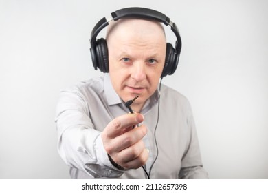 Bald Man With Headphones On His Head And An Open Plug In His Hand. Search For A Sound Source