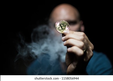 Bald Man Holds A Bitcoin In A Smoky Dark Place.