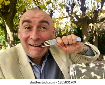 Bald Man In Jacket Picking His Fork In The Teeth In Restaurant