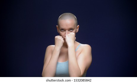 Bald Woman Boxing To The Camera Against A Dark Background