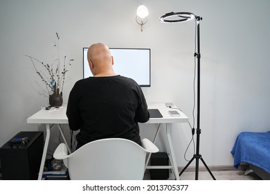 Bald Woman Looking At The Screen While Sitting At The Table With Her Stationary Computer