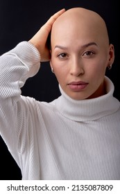 bald woman on black studio background, looks at camera, confident. she feels awkward due to falling hair. concept of oncology and effects of chemotherapy. portrait. people, healthcare concept