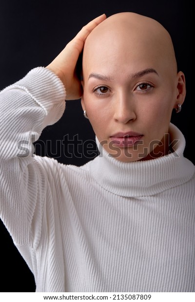 bald woman on black studio background, looks at\
camera, confident. she feels awkward due to falling hair. concept\
of oncology and effects of chemotherapy. portrait. people,\
healthcare concept