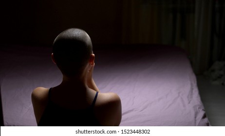 A Bald Woman Prays On Her Knees By The Bed. Back View. Copy Space