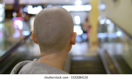 Bald Woman Rises Up On The Escalator. Turns And Looks At The Camera.