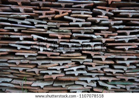 Bales ceramic shingles for roofing. Stack of old ceramic roof tiles, textured background.