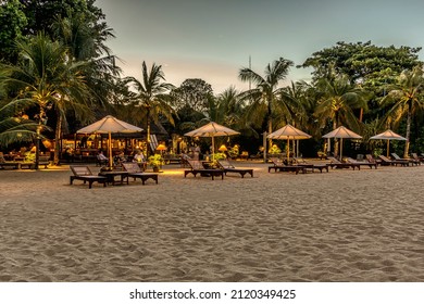 Bali Beach With Sunbeds At Night And People Relaxing In The Restaurant, Bali, April 26, 2018