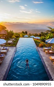 Bali, Indonesia: December 10 2017 - A man was swimming in an infinity pool during sunset time. The pool was located high in elevation, so he felt like swimming into the clouds.