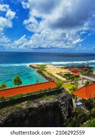 Bali, Indonesia - December 23 2021 : local beach at Bali Island called " Melasti Beach" filled with blue waves, traditional roofing villagers houses and sky view background