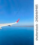 Bali, Indonesia - December 23, 2023. Picture of the wing of the plane of Air Asia in the blue sky before landing.