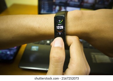 BALI, INDONESIA JUNE 09 2022 : A Man Using And Touch Screen Honor Band 5 Smartwatch That Huawei Manufactured