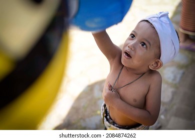 Bali, Indonesia, June 26, 2016. A Shirtless Kid Happily Try To Reach Balloon On Toys Stall.