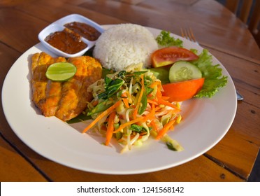 Bali Indonesia November 2018: Fish Cooked Mahi Mahi Served With Rice, Lime, Peanut Sauce And Vegetable Salad.