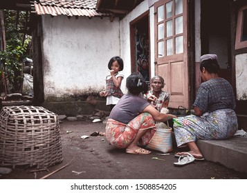 Bali, Indonesia - Sep 19, 2019: Family Portrait Of A Rural Indonesian People Sitting On The Street In Front Of Their Traditional House.