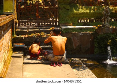 Bali / Indonesia, September, 24, 2018 - A father and his son praying in a temple of Balinese hinduism in Gunung Kawi - Shutterstock ID 1404875351