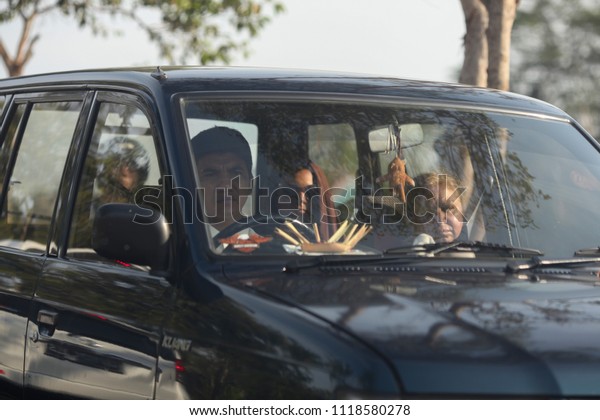 Bali Island, Indonesia -\
08/05/2015:  Local Balinese people in the car driving along the\
road.