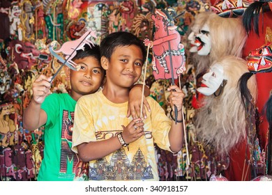 BALI ISLAND, INDONESIA - JULY 11, 2015: Smiley Balinese Children Have Fun And Play With Characters Of Traditional Shadow Puppets - Wayang Kulit. Arts, Crafts And Culture Festivals Of Indonesian People