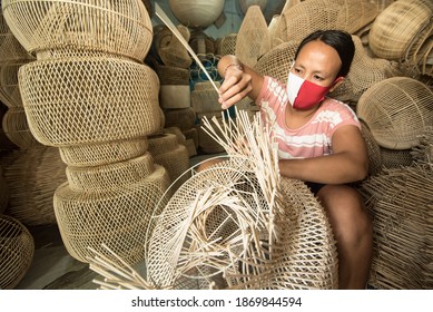 Bali,Indonesia - December, 2020 : The local artisan making balinese handicrafts for tourism destination and local people in Bali Island, Indonesia. She use masks to protect themselves from virus.