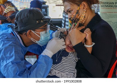 BALI,INDONESIA-JUN 14 2021: An ENT doctor is examining the ears, nose and throat of a pediatric patient. ENT examinations are very risky because they come into direct contact with patients