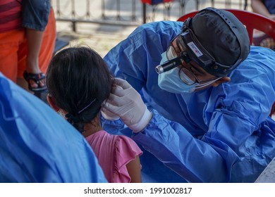 BALI,INDONESIA-JUN 14 2021: An ENT doctor is examining the ears, nose and throat of a pediatric patient. ENT examinations are very risky because they come into direct contact with patients